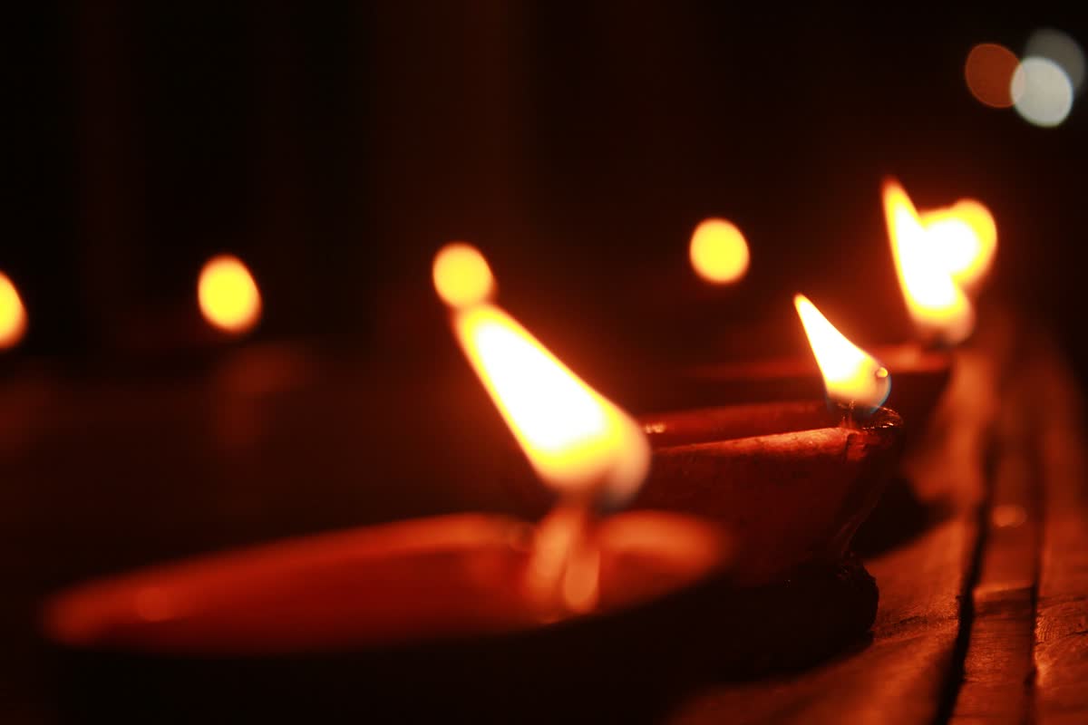 A row of lit clay diyas glowing in the dark